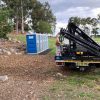 Crane assembly setting up portable toilets for an event in sydney